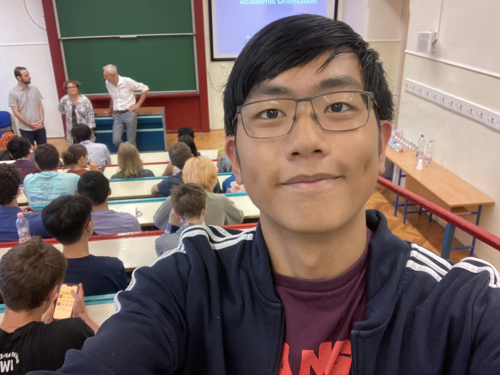 Skyler in a big lecture hall for orientation. Behind him are three teachers/administrators and soon-to-be classmates.
