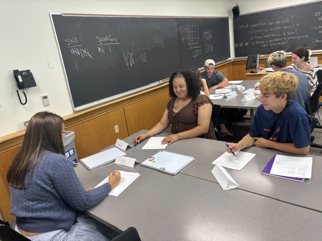 A team of three rotates playing and note-taking roles as they try to understand how to win this game.